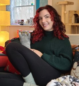 A red haired woman holding a gray stuffed cat